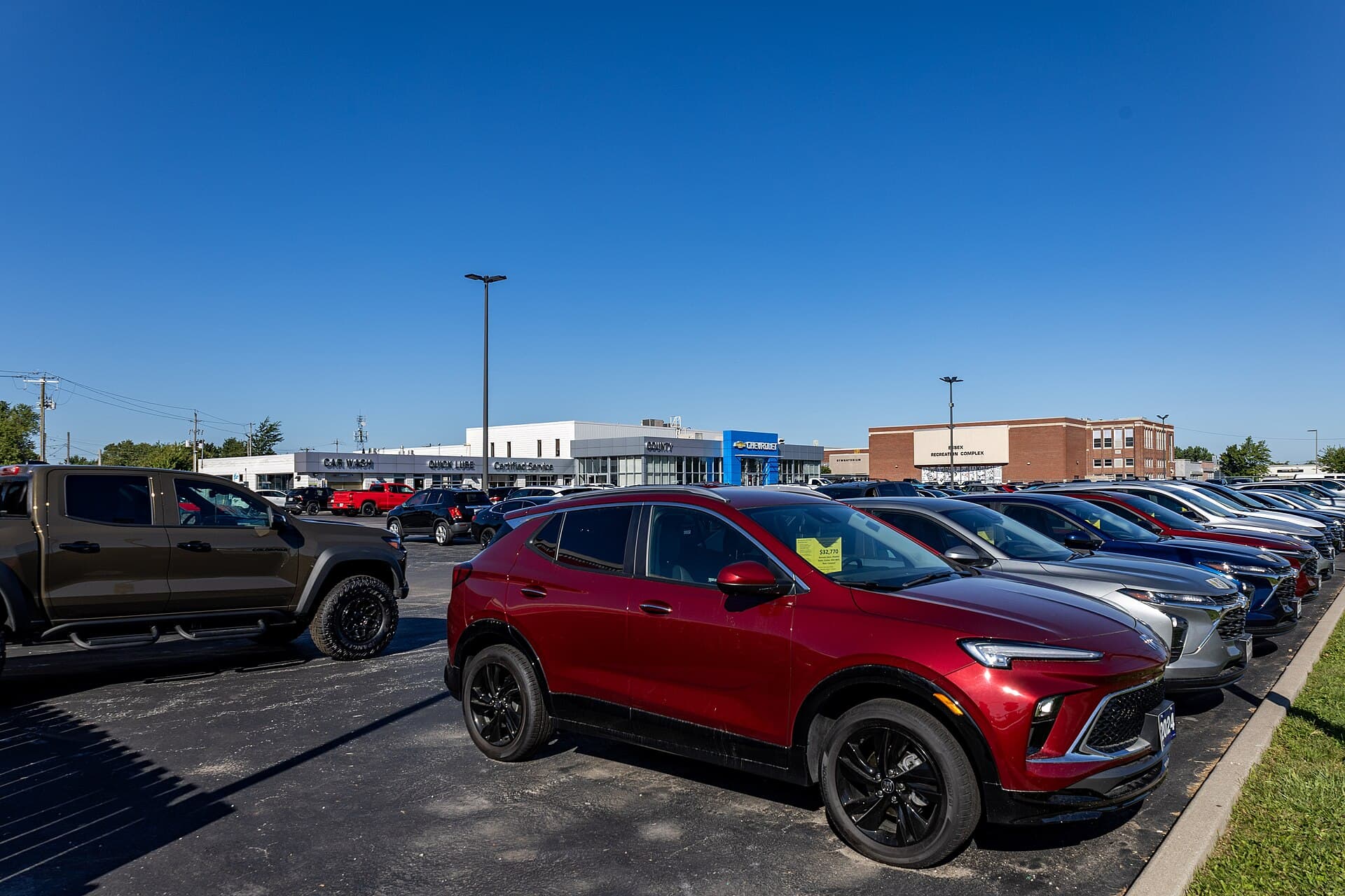 Cars parked in rows on a dealership lot on a clear day.